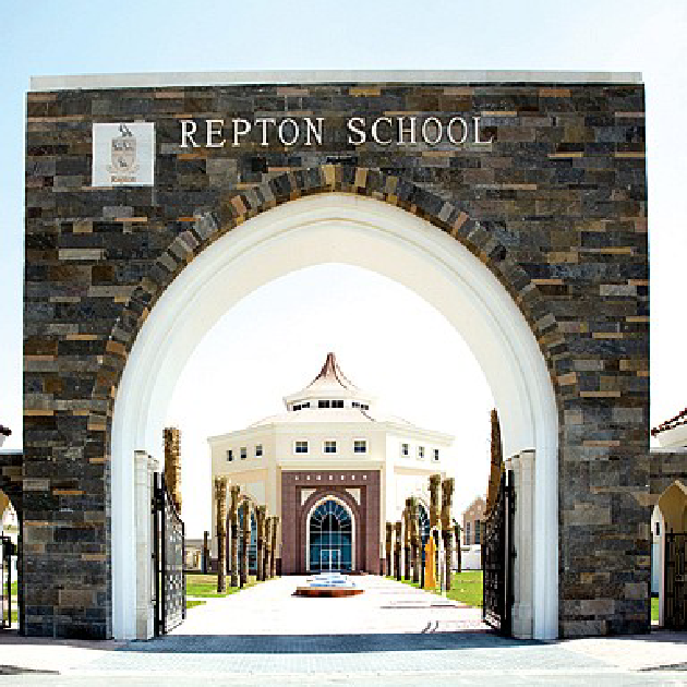 Repton School Dubai campus with students walking past traditional-style architecture and green fields
